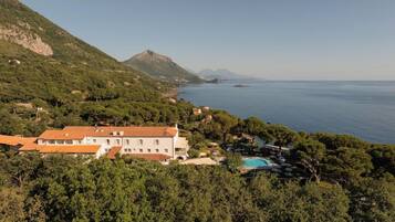 Una proprietà costiera con un edificio grande, una piscina e vegetazione lussureggiante.