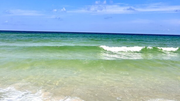 Une plage avec une eau turquoise cristalline et un ciel dégagé.