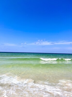 Ein Strand mit klarem türkisblauem Wasser und blauem Himmel.