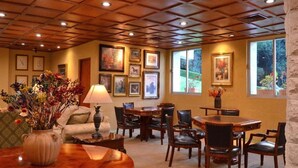 A dining area with wooden tables and chairs, framed artwork on the walls, and a vase with flowers on the table. - Hotel El Paraiso (Mineral del Chico)