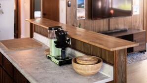 Une cuisine moderne avec un lambris en bois, une cuisinière encastrée et des luminaires suspendus.