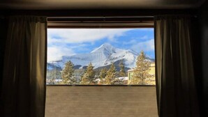 A room with a large window overlooking a snowy mountain landscape. - Studio getaway steps away from Big Sky Resort (Big Sky)