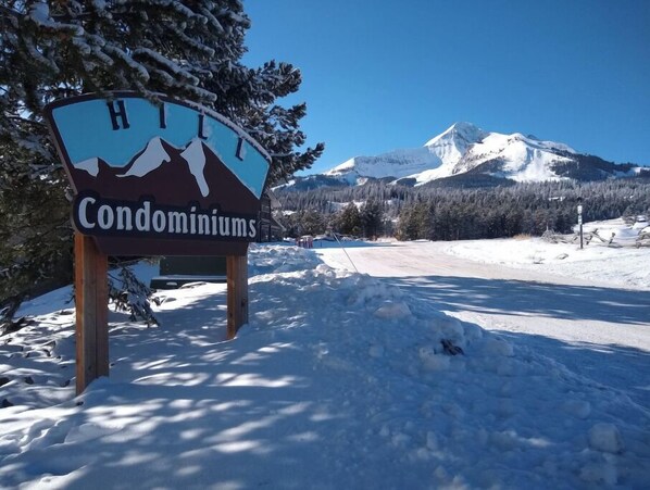 A sign for Hill Condominiums with a mountain view in the background.