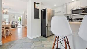 Una cocina moderna con armarios blancos, electrodomésticos de acero inoxidable y una zona de comedor con mobiliario de madera.