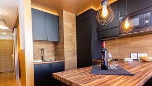 A modern kitchen with a wooden countertop, black cabinets, and pendant lighting. - Lighthouse Friendly Holiday Home (Playa del Inglés)