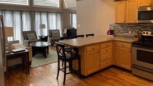 A modern kitchen with wooden cabinets, a stainless steel oven, and a dining area with a table and chairs. - Lake House with stunning view of Lake Cumberland (Somerset)