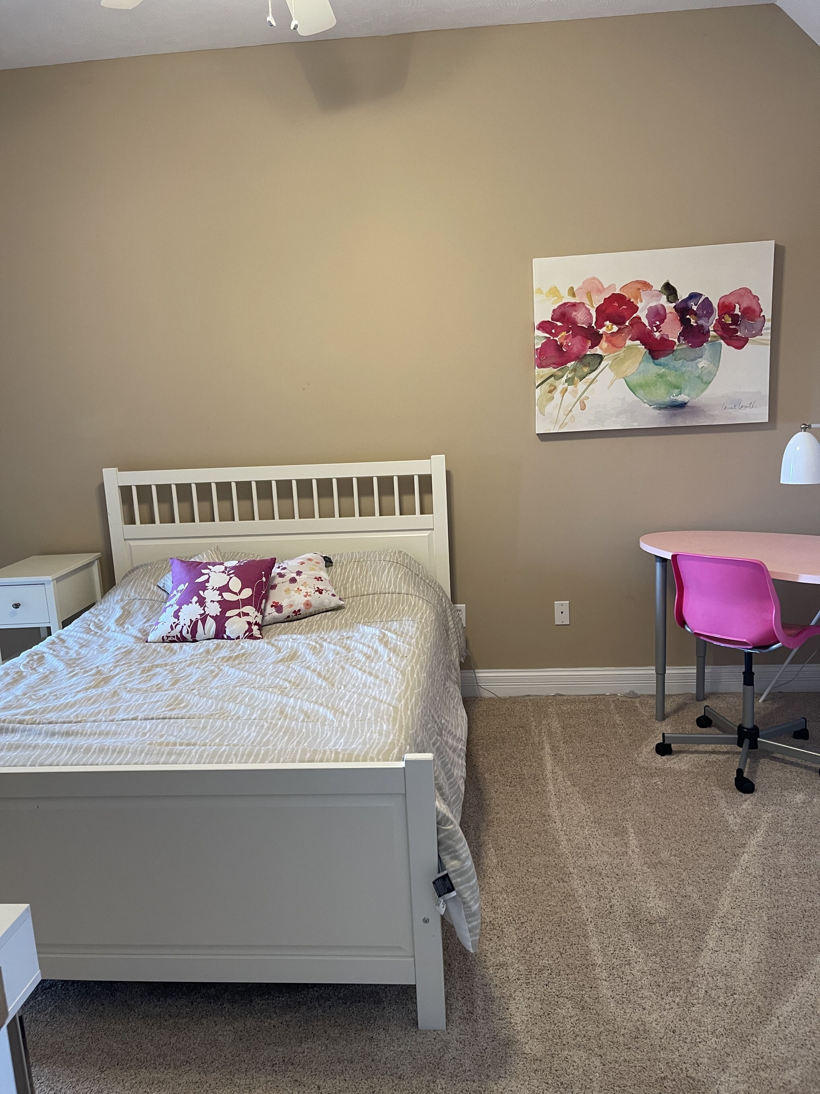 Een slaapkamer met een bed, een bureau en een stoel.