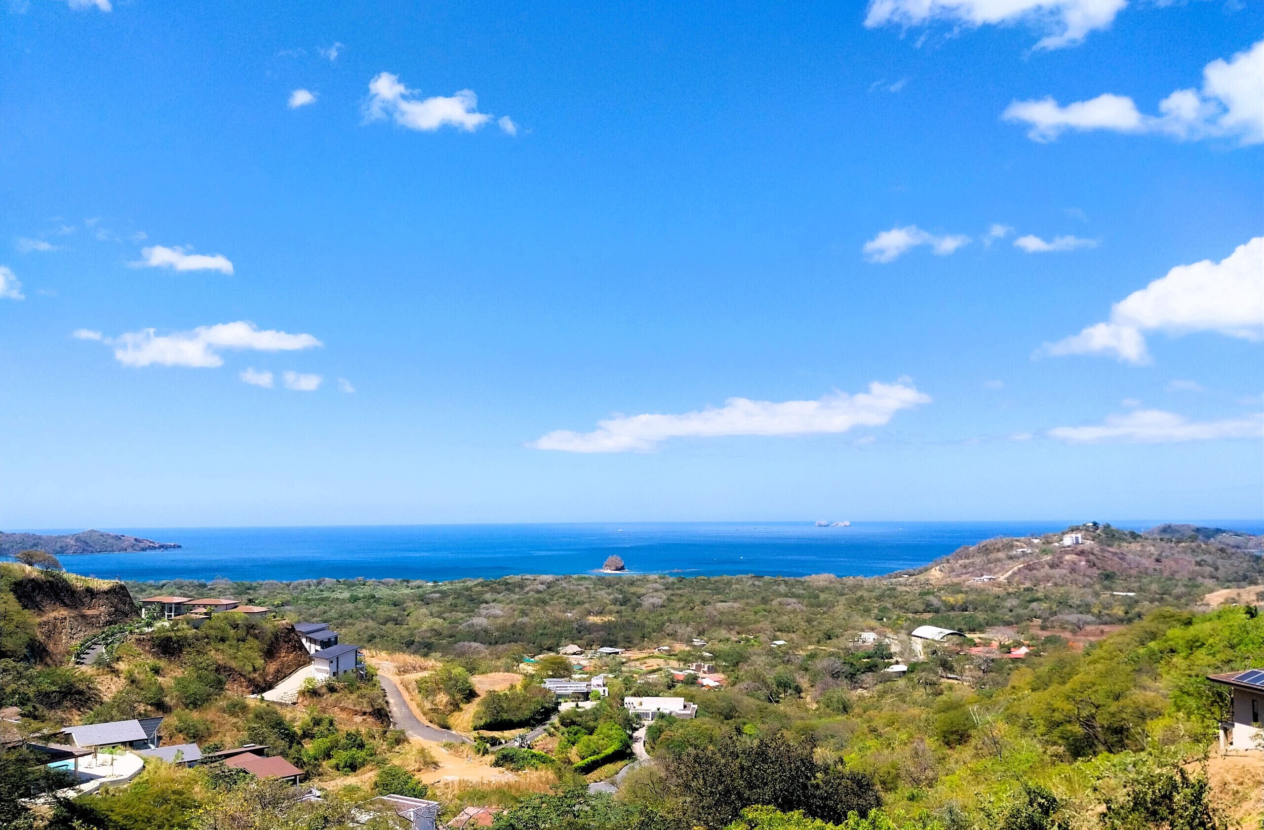 A coastal landscape with scattered houses and a clear view of the ocean.
