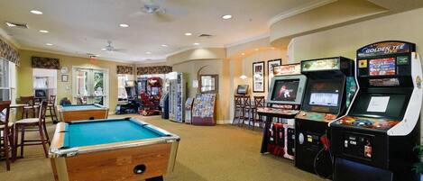 A pool table, arcade games, and a billiards table in a room with carpeted floors and recessed lighting.