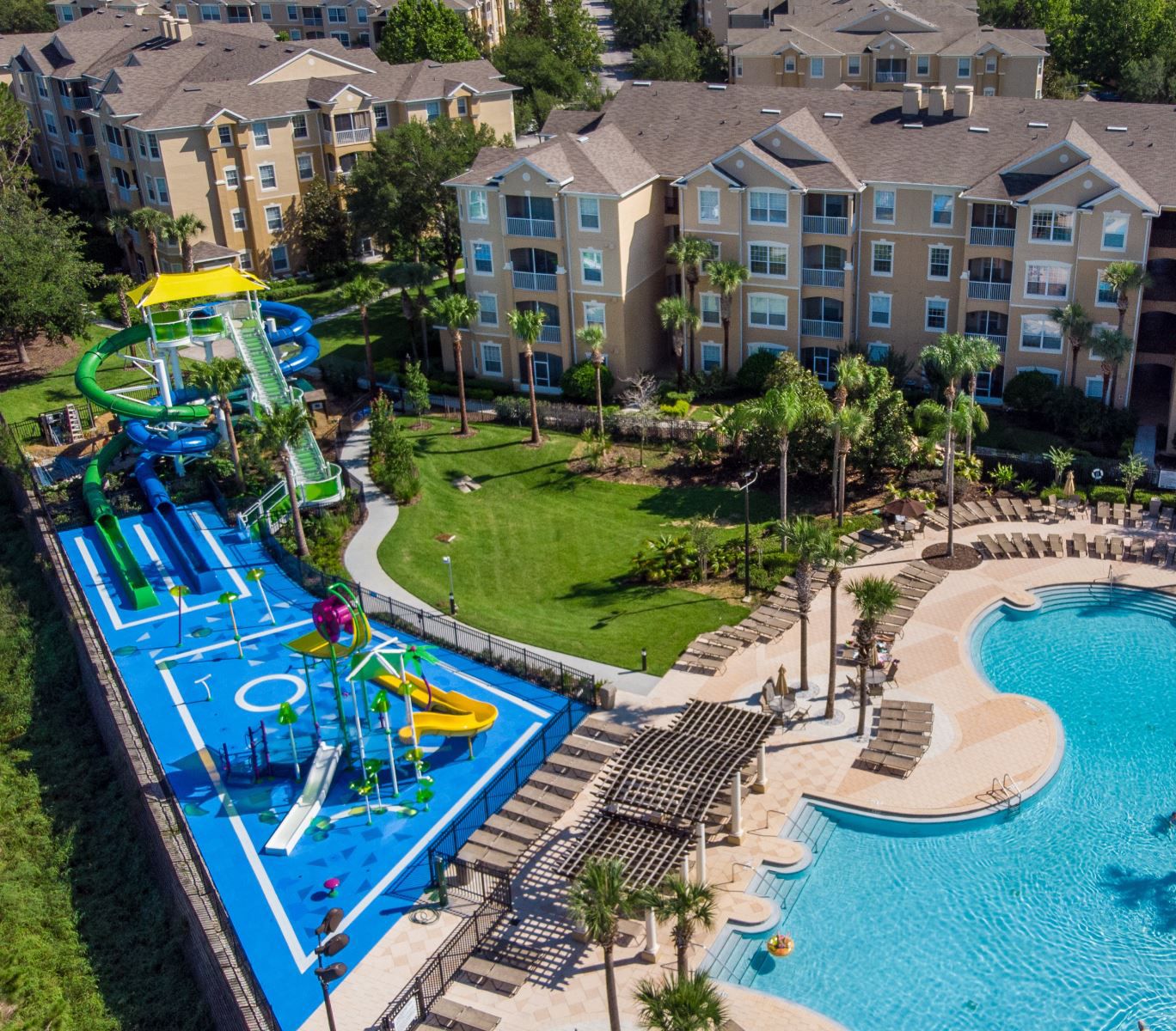 Eine Luftaufnahme eines Resorts mit Schwimmbad, Wasserrutschen und einer angelegten Fläche mit Palmen.