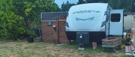 Una caravana StarCraft Super Lite estacionada en un área con césped, una cerca de madera y árboles al fondo.