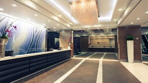 A modern reception area with a reception desk, a large abstract mural, and a hanging light fixture. - Las Vegas Timeshare at Wyndham Desert Blue (Las Vegas)