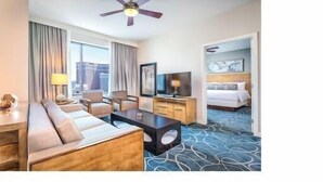 A hotel room with a sofa, coffee table, TV, and a bed. - Las Vegas Timeshare at Wyndham Desert Blue (Las Vegas)