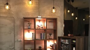 Una habitación acogedora con una estantería de madera, una mesita y un refrigerador.