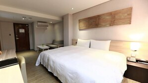 Habitación de hotel con una cama grande, una mesita pequeña, una silla y un escritorio.
