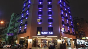 Un hotel con varios pisos, ventanas iluminadas y un cartel que indica que es el Hotel Sime 73.