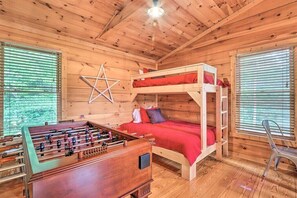 Ein Zimmer in einer Holzhütte mit Stockbetten, einem Kicker und einer Stern-Dekoration an der Wand.
