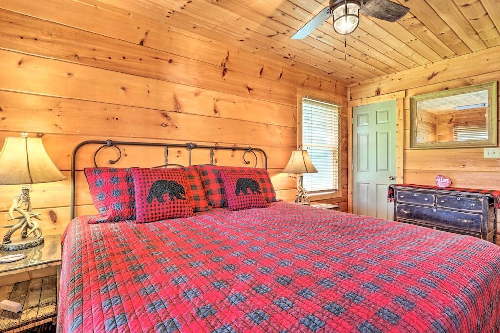 Ein Zimmer in einer Holzhütte mit einem Bett, zwei Lampen, einem Schminktisch und einem Spiegel.