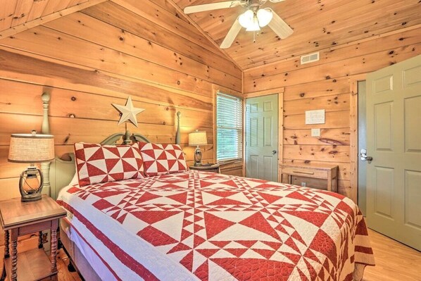 Un dormitorio de cabaña de madera con una cama, un ventilador de techo, una decoración de estrellas y una puerta.