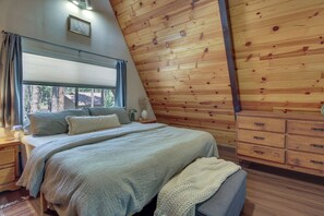 A bedroom with a bed, bedside tables, a dresser, and a window with curtains.