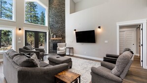 A modern living room with a stone fireplace, large windows, and a flat-screen TV. - Air-Conditioning, Privacy, Family Retreat! (Durango)