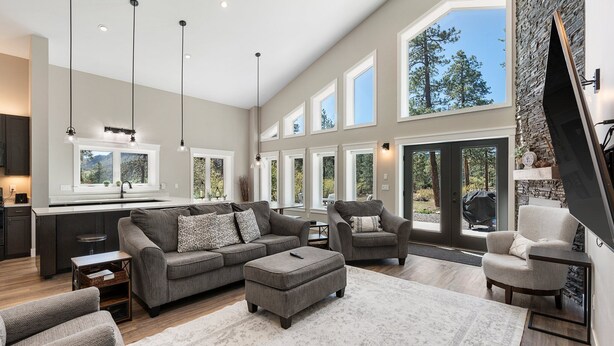 A spacious living area with a large sofa, ottoman, and armchairs, a kitchen with a large window, and a stone accent wall. - Air-Conditioning, Privacy, Family Retreat! (Durango)