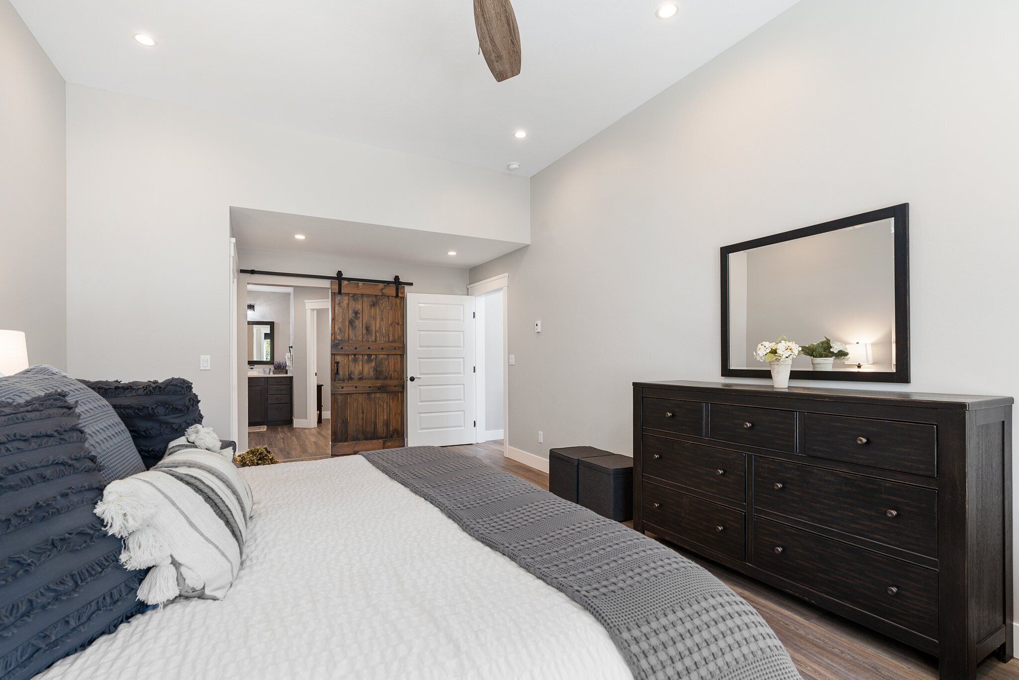 A bedroom with a large bed, dark wooden dresser, and a mirror above it.