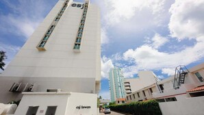 Un edificio alto y blanco con la leyenda "esj towers" en su fachada, que presenta múltiples ventanas y un cielo despejado al fondo.