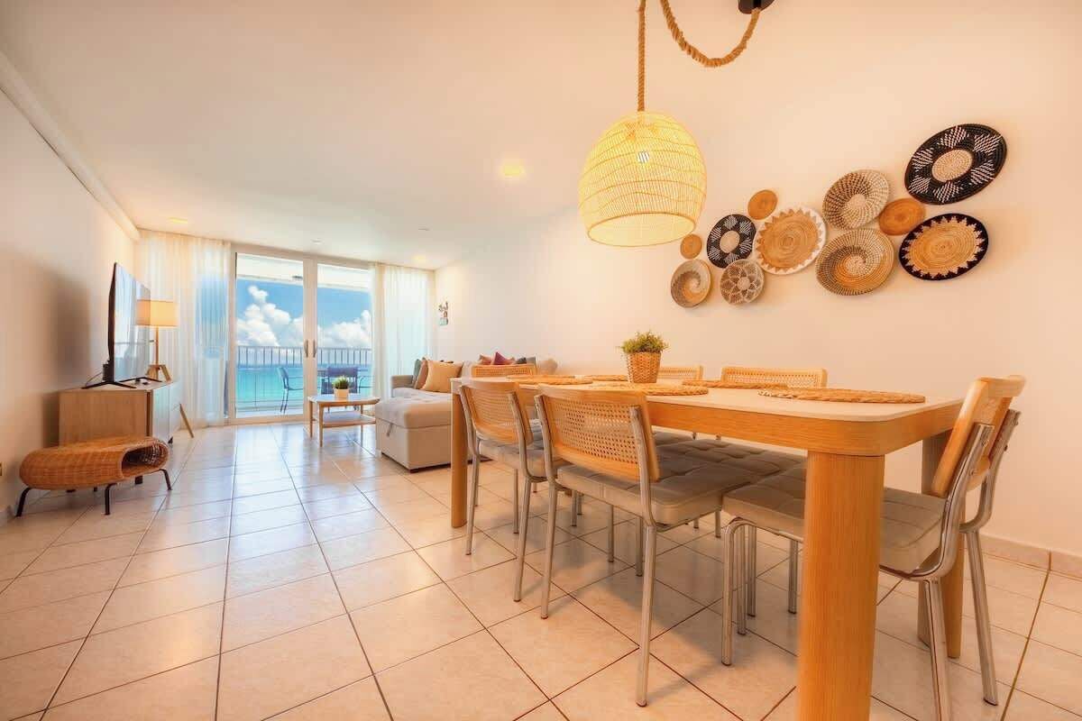 A dining area with a large table, chairs, and a hanging light fixture.