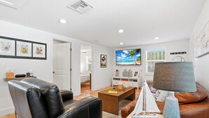 A modern living room with a leather sofa, a coffee table, and a TV. - Canal-Front Oasis in Terra Ceia: Pool, Patio, Dock (Terra Ceia)