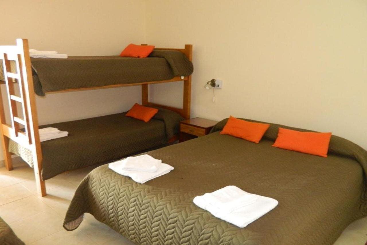 Une chambre avec un lit superposé, comportant deux lits, chacun agrémenté d’un oreiller orange et d’une serviette blanche sur le lit du bas.