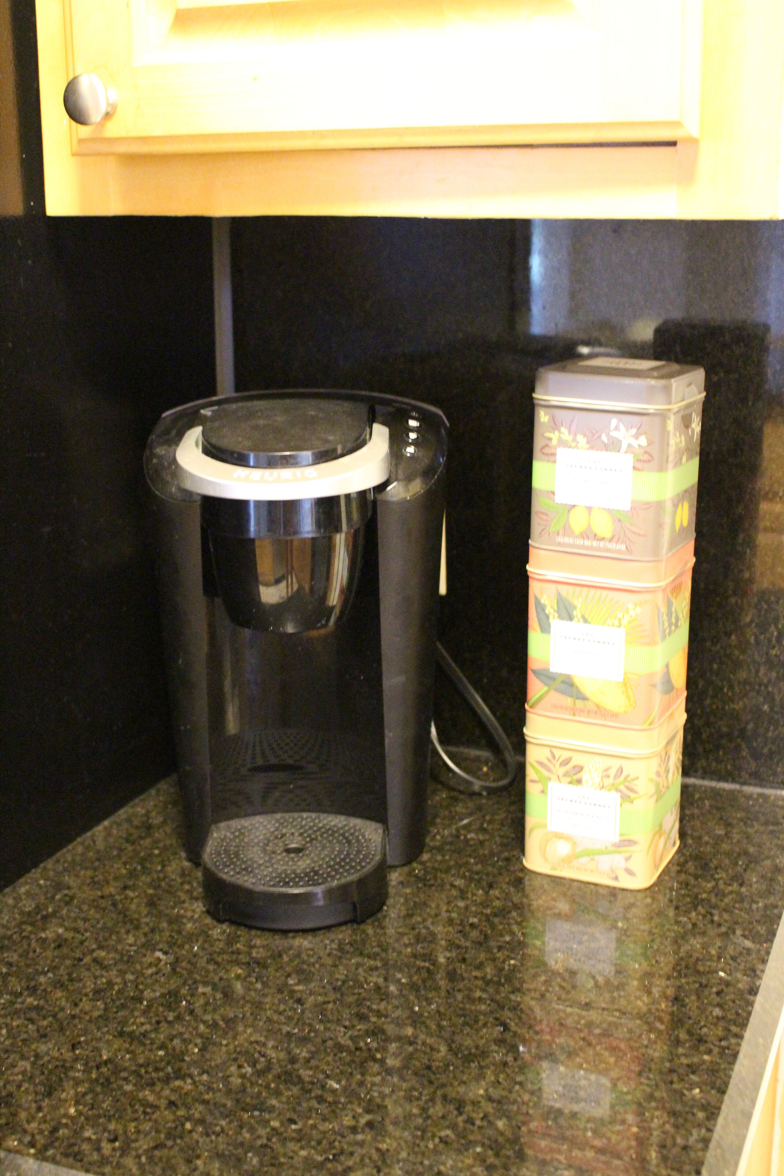 A coffee maker and stacked containers on a kitchen counter.