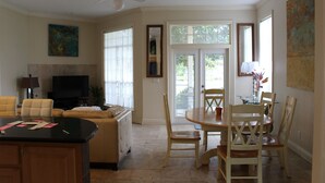 Un grand espace de vie comprenant un canapé, un téléviseur et une table à manger avec des chaises.