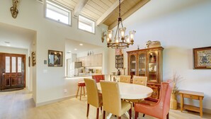 Un vaste espace dédié à la salle à manger, avec une grande table ovale, des fauteuils en cuir et un buffet en bois doté de portes en verre.