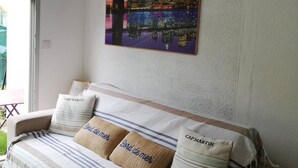 A living room with a sofa, two pillows, and a cityscape painting on the wall.