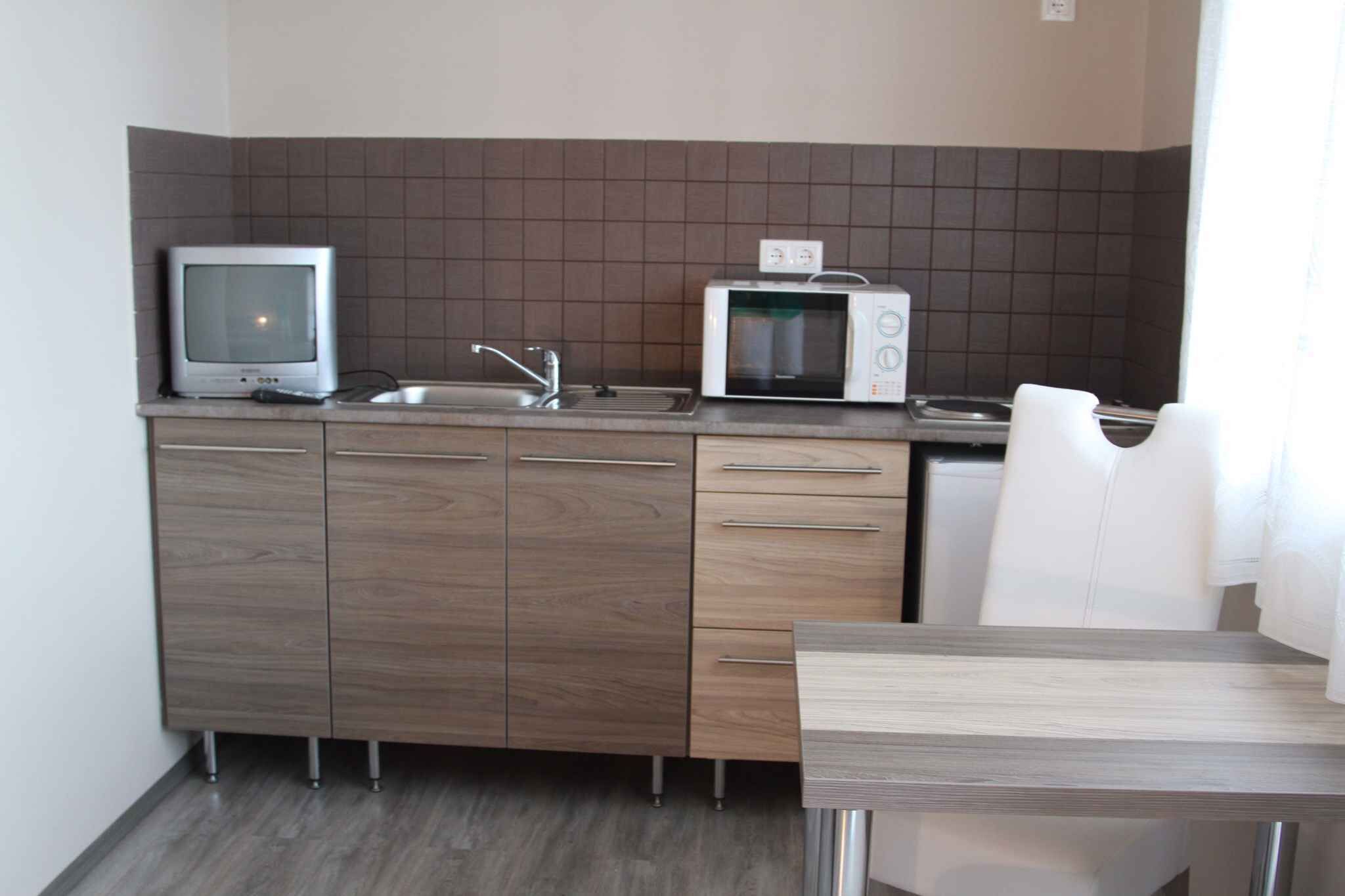 A compact kitchen with a microwave, a small sink, and a wooden cabinet.
