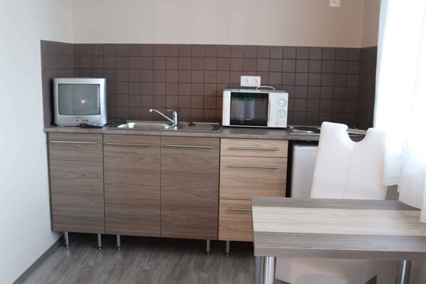 A compact kitchen with a microwave, a small sink, and a wooden cabinet. - Studio child-friendly with internet and barbecue facilities (Balatonföldvár)