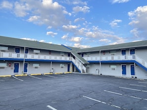A two-story motel with a parking lot, blue and white exterior, and a staircase connecting the floors.