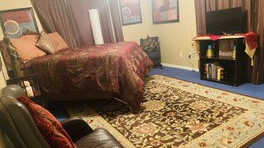 Een slaapkamer met een bed, een boekenkast, een televisie en een stoel.