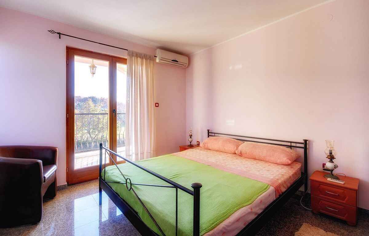 A bedroom with a bed, a nightstand, a chair, and a window with curtains.