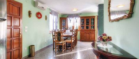 A dining area with a wooden table and chairs, a glass-top console table with a vase, and a large mirror on the wall.