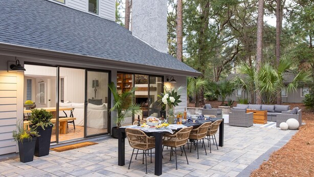 Un espace repas extérieur moderne, avec une table et des chaises, entouré de plantes en pot et agrémenté d’une terrasse.