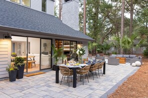 Un espace repas extérieur moderne, avec une table et des chaises, entouré de plantes en pot et agrémenté d’une terrasse.