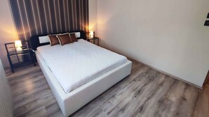 Un dormitorio moderno con una cama grande, suelo de madera y pared a rayas.