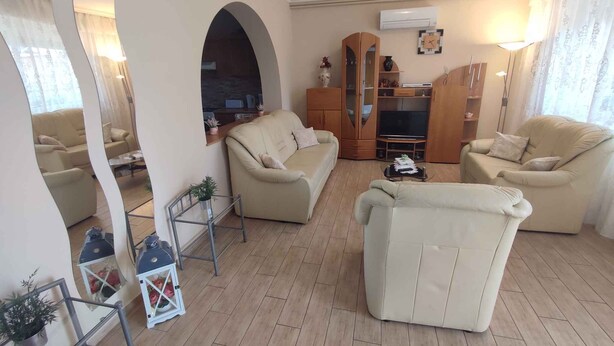 Una sala de estar con sofá, sillones, televisor y aparador de madera.