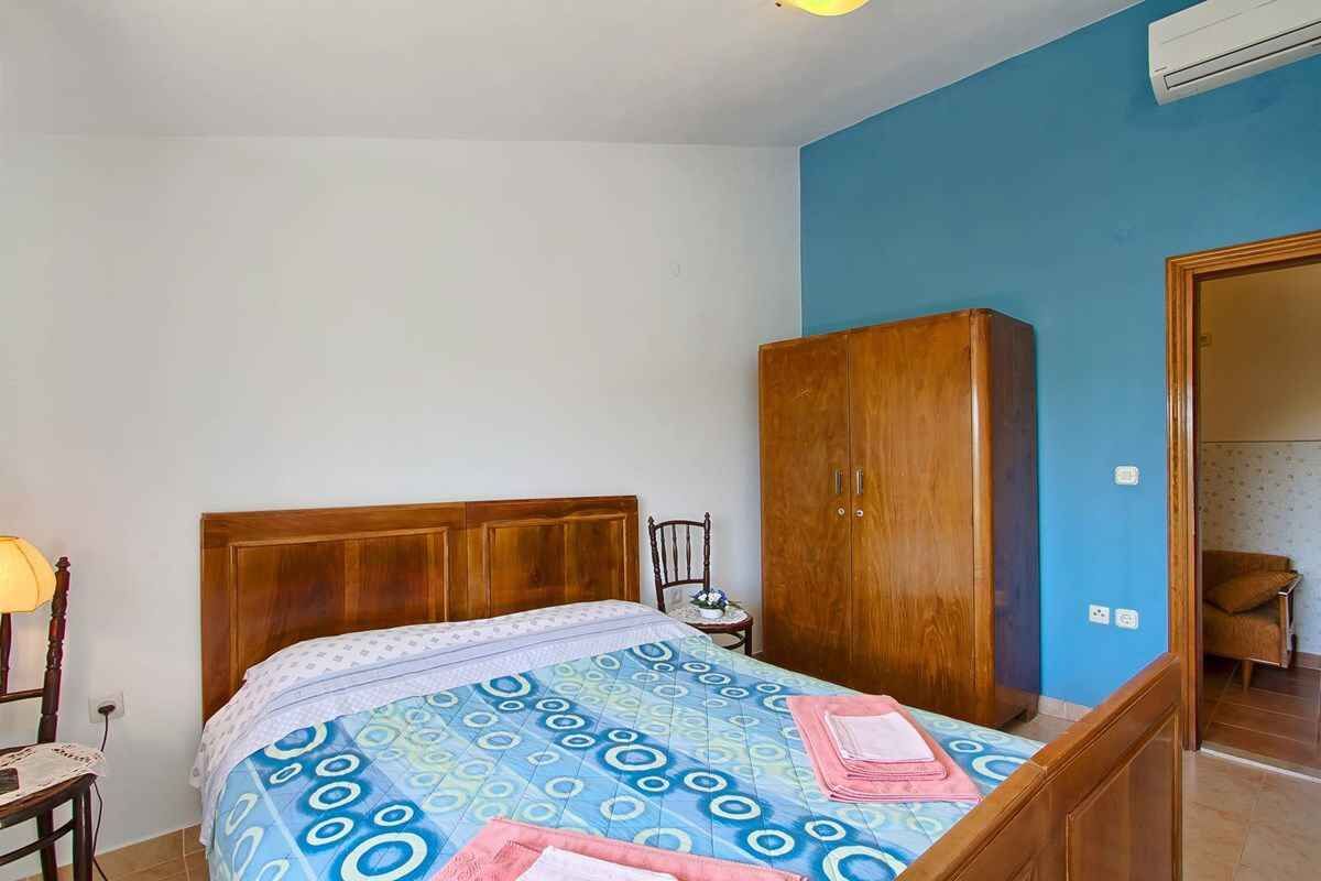 Une chambre à coucher avec un lit, une armoire en bois et une chaise.