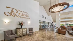 Eine großzügige Lobby mit hoher Decke, einem großen Kronleuchter und einem Empfangstresen mit der Aufschrift 'Welcome'.