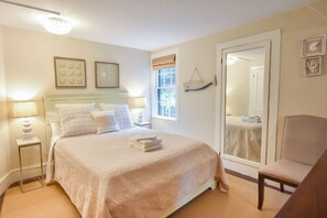 Una camera da letto ordinata con un letto, lampade da comodino, una sedia e una finestra.