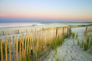 Una spiaggia con una recinzione di legno e dune sabbiose.