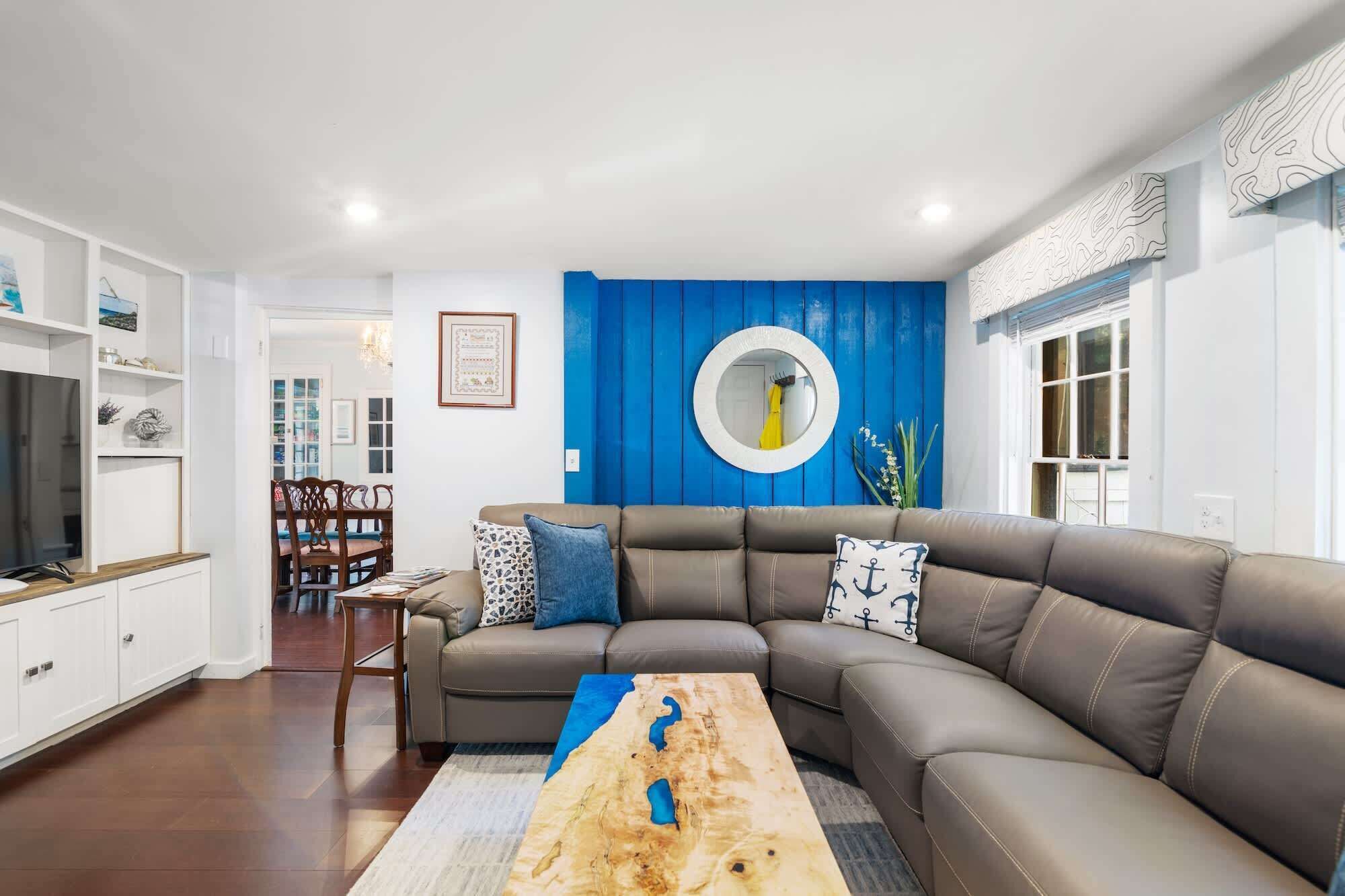 A modern living room with a sectional sofa, a wooden coffee table, and a blue accent wall.